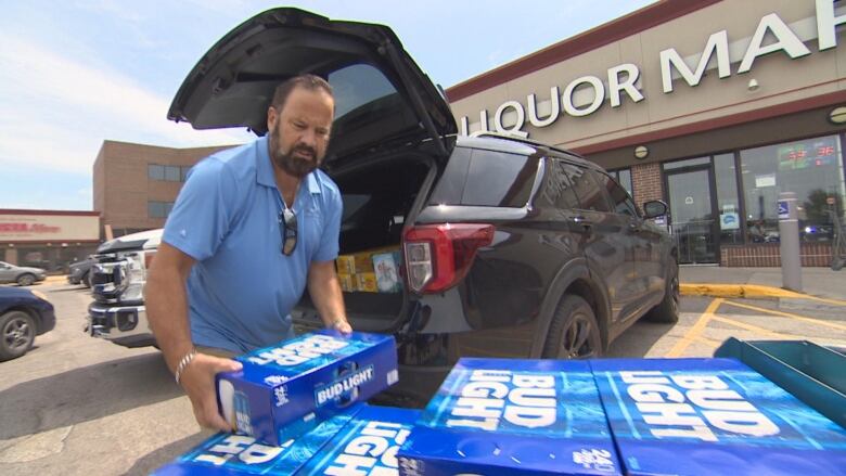 A man loading cases of Bud Light into the trunk of an SUV.