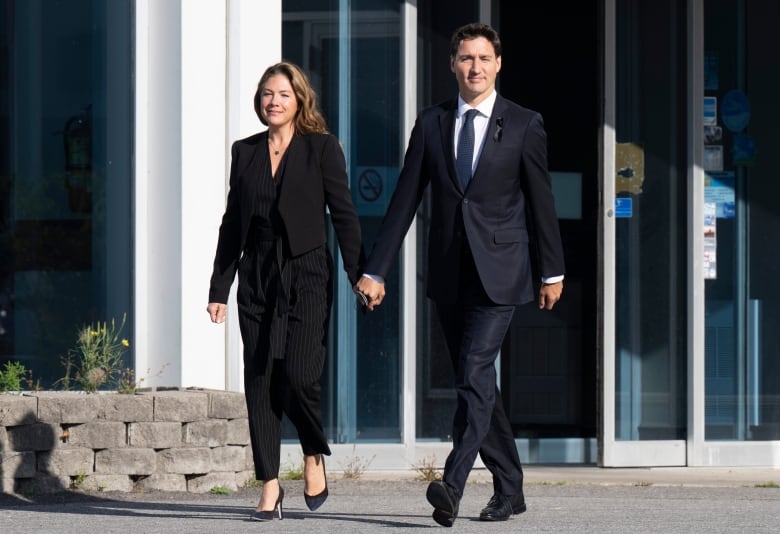 A man and a woman walk holding hands.