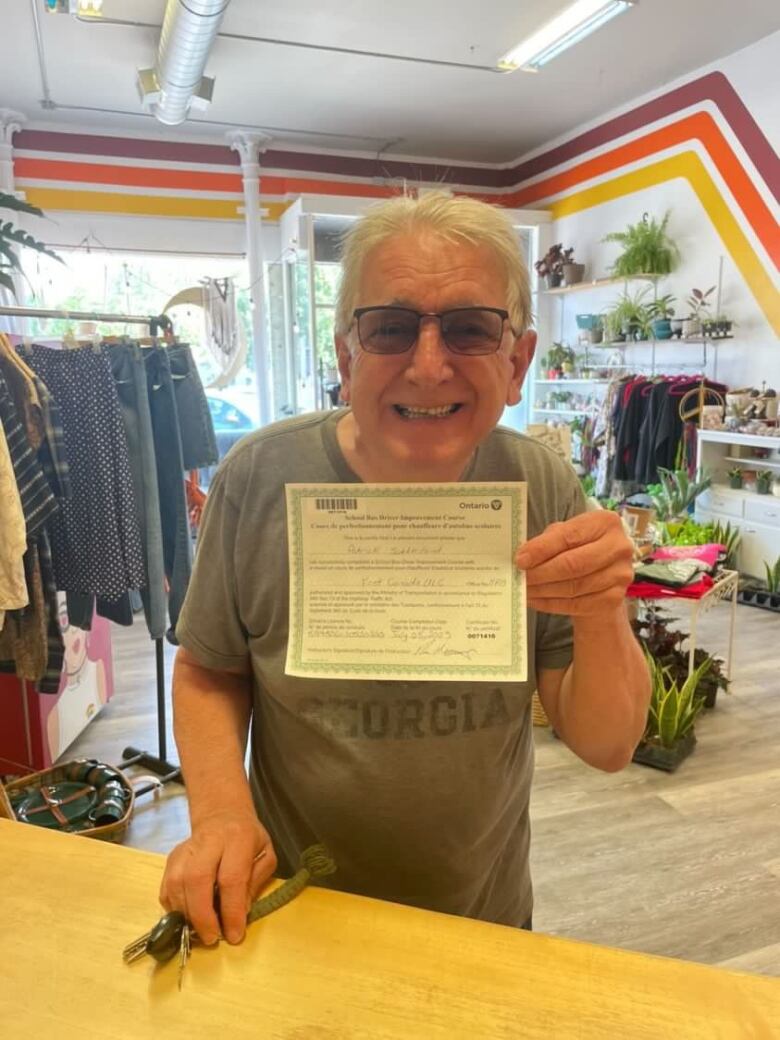 A man in a clothing store holding up a piece of paper that serves as a certificate. 