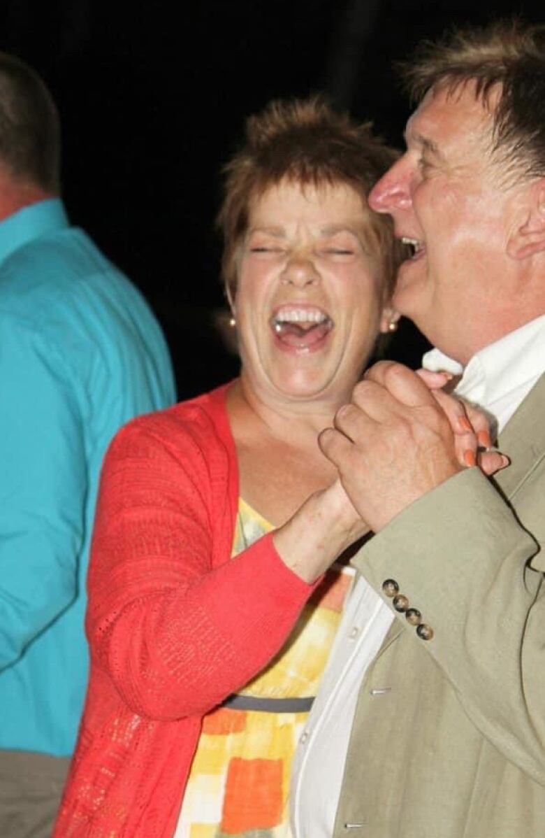 A couple dancing at a formal event, laughing. 