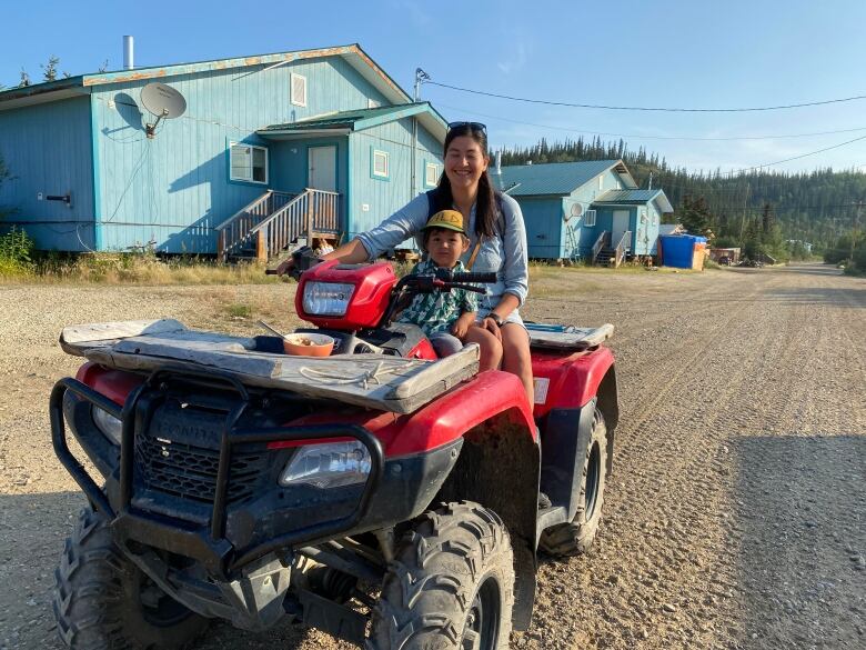 A smiling woman and her son on a quad.