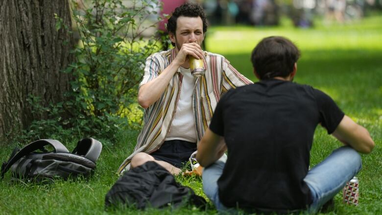 Sitting with a friend on the grass, a man drinks a beer at a public on the first day the City of Toronto permits drinking in 27 public parks as part of a pilot lasting until Oct. 9.