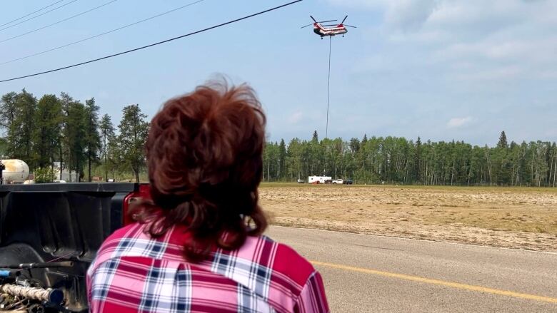 A woman watches a helicopter