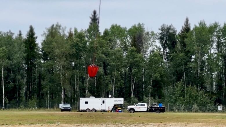 A helicopter carries a bucket of water