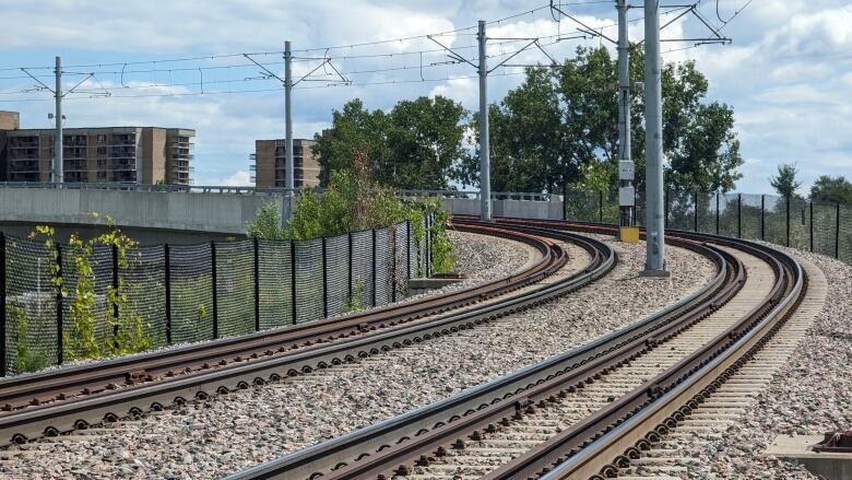 Tracks go around a curve. In the distance, restraining rails, located within the curve are painted bright orange.