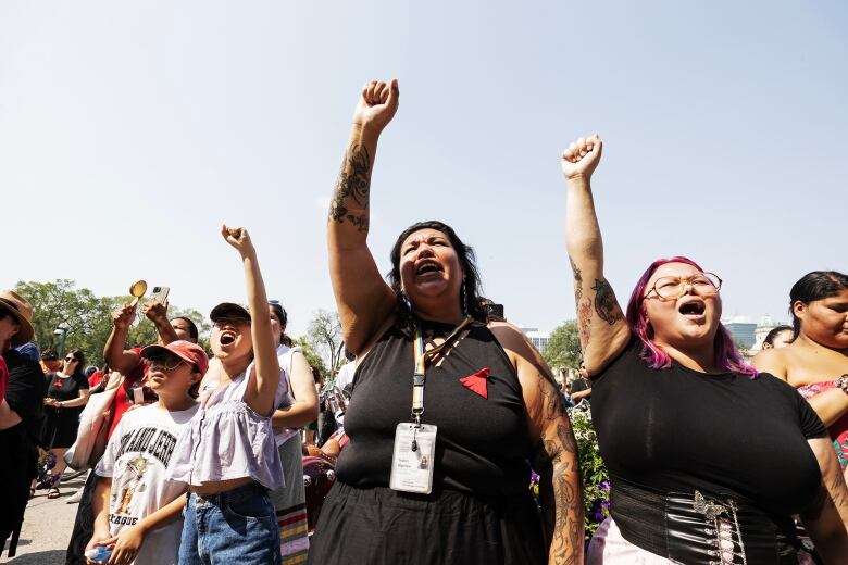 People standing in a line, some holding up their fists, as they demand action from governments. 