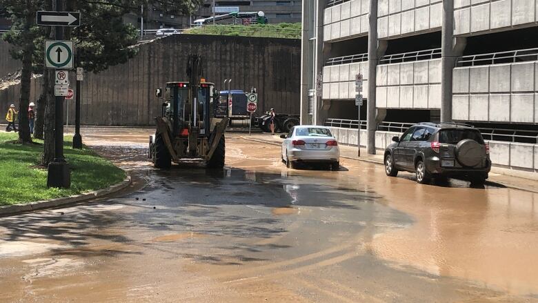 cars parked next to a parking garage in a pool of brown water.