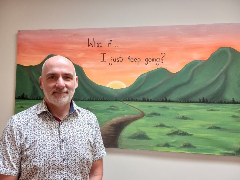 Man in dress shirt stands in front of a painting.