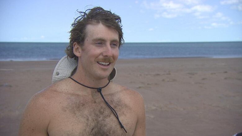 A man shirtless on the beach.