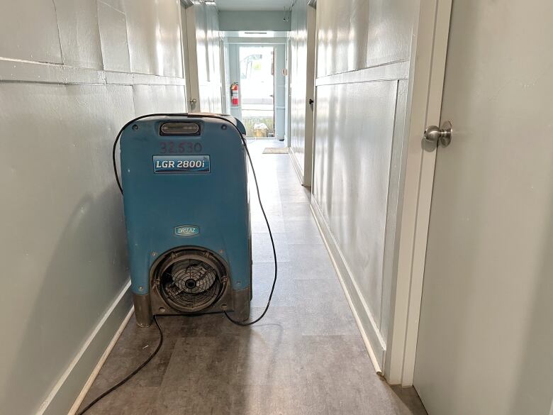 A large industrial-sized dehumidifier is shown in a hallway.