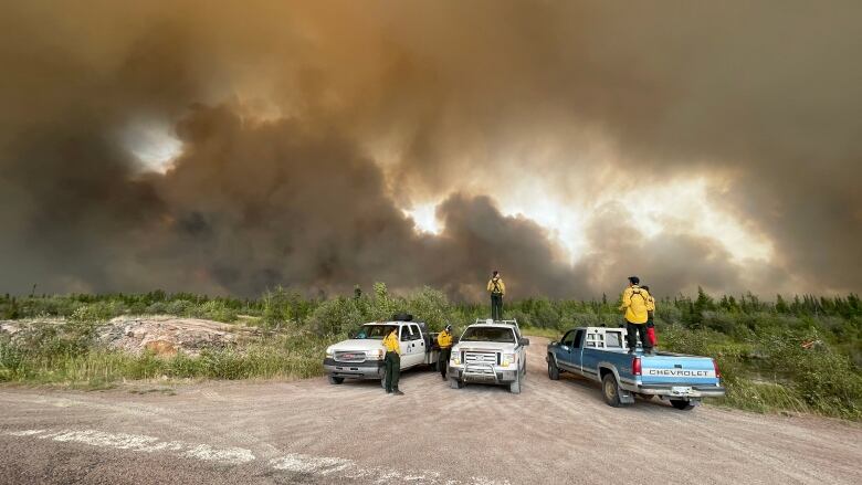 Huge plume of smoke, people on trucks.