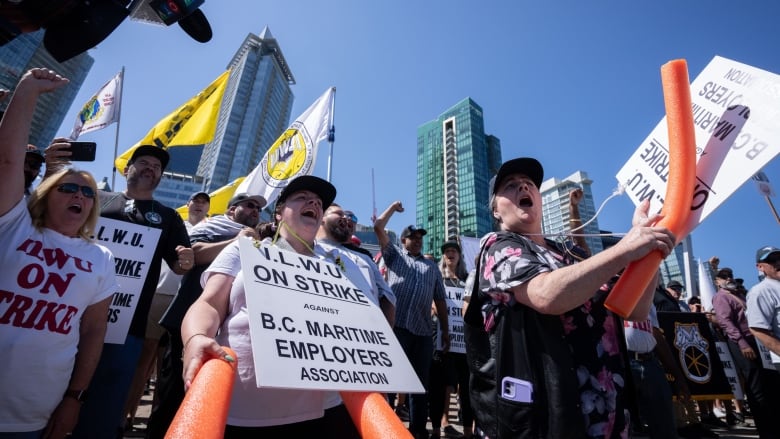 People wearing sandwich boards that read 'I.L.W.U. On Strike against B.C. Maritime Employers Association' are pictured at a protest.