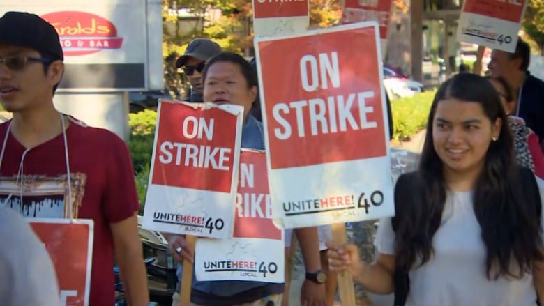 Men and women walk with red and white union signs.