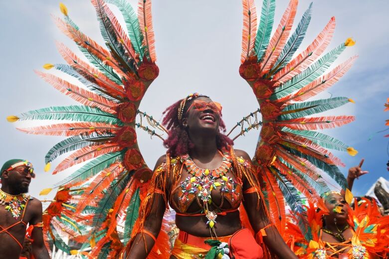 With dancers behind her, a woman wearing a colourful carnival costume during the Toronto Caribbean Carnival grande parade