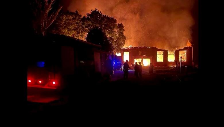 A fire engulfed in flames burns during the night.