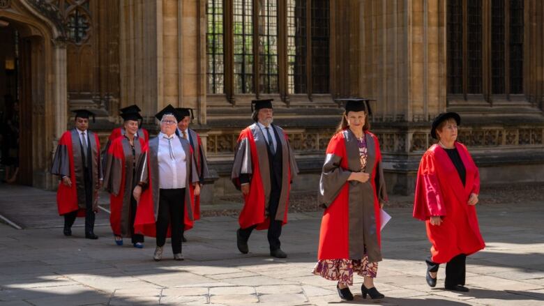 People walk outside at Oxford University for an honorary degree ceremony.