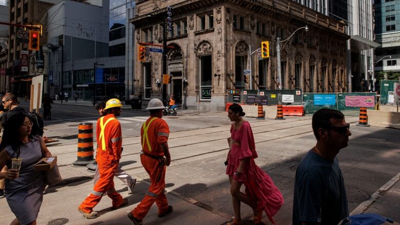 Pedestrians cross a busy intersection during a heat advisory for downtown Toronto on July 28, 2023.