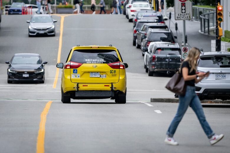 A yellow van taxi drives down the street