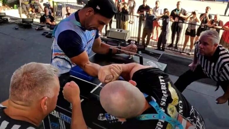 Men arm-wrestling while referees look on