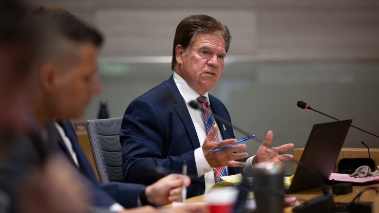 A man in a suit speaks into a microphone