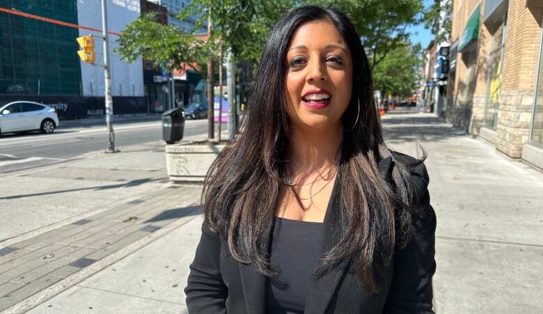 Liza Amlani standing on the street being interviewed by CBC. 