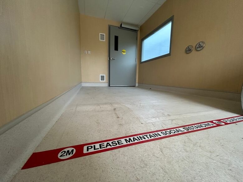 An empty, repurposed shipping container with tape on the floor asking visitors to maintain a 2-metre distance from one another at all times will soon be repurposed into a food bank