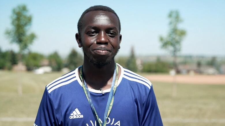 A man in a dark blue football jersey is seen smiling.