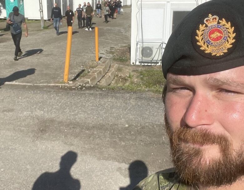 Closeup of a soldier in uniform in front of a line of other troops. 