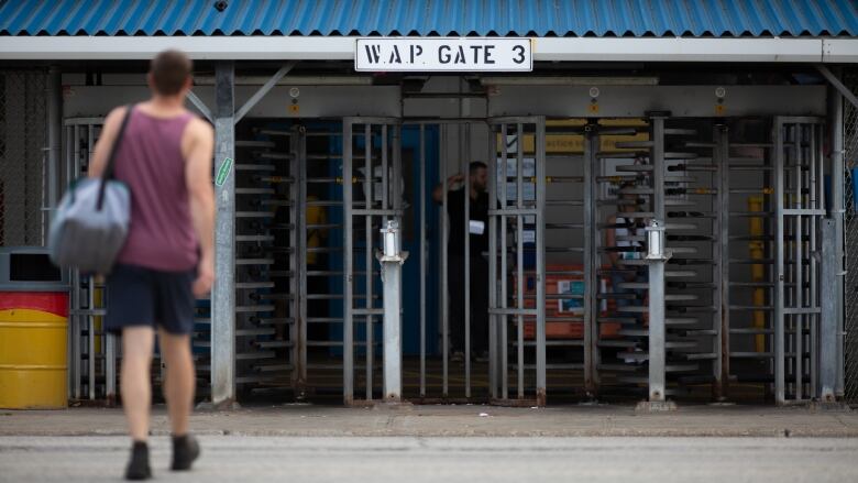 A man walks towards a gate. 