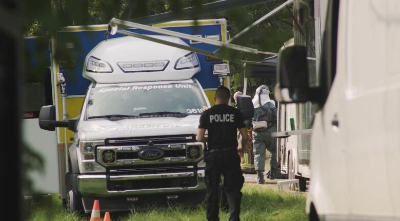 Police walk in between vehicles.