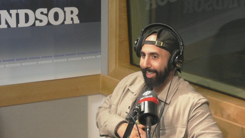 A man wearing headphones speaks into a microphone in the CBC Windsor studio