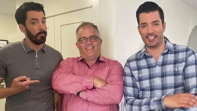 Three men stand looking at the camera. 