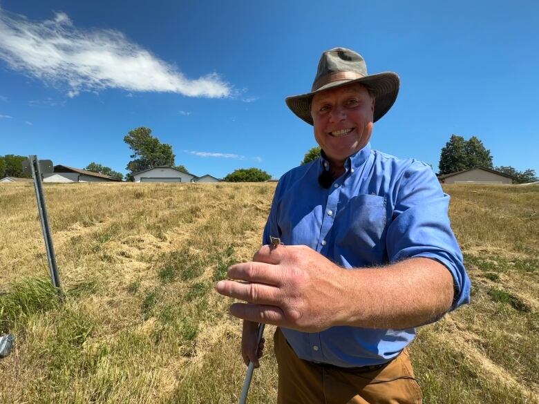 James Tansey, Saskatchewan's provincial entomologist, stands for a photo with a two-striped grasshopper on his finger.