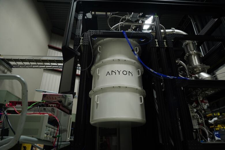 A white cylinder hanging from a metal frame. 