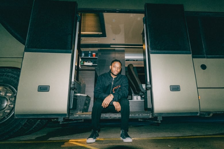 Hip-hop artist, ARDN, sits on a tour bus.