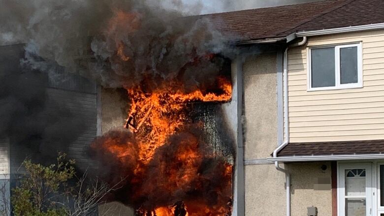 A townhouse engulfed in flames and black smoke