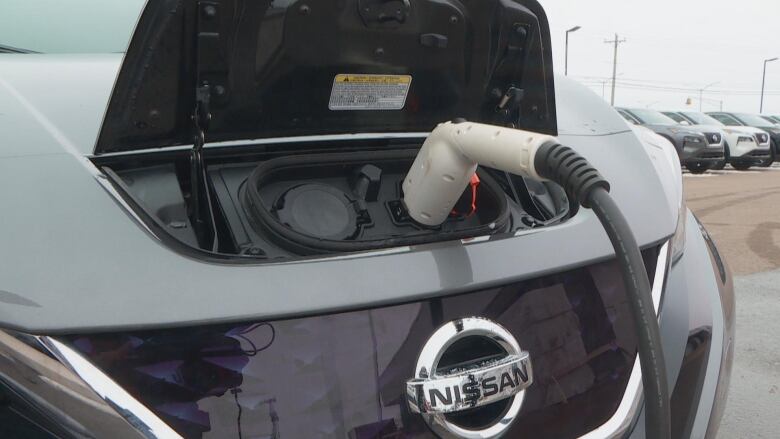 A charger is plugged into the front of an electric vehicle 