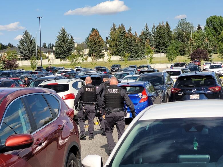 Cars at a parking lot are visible with police officers in uniform.