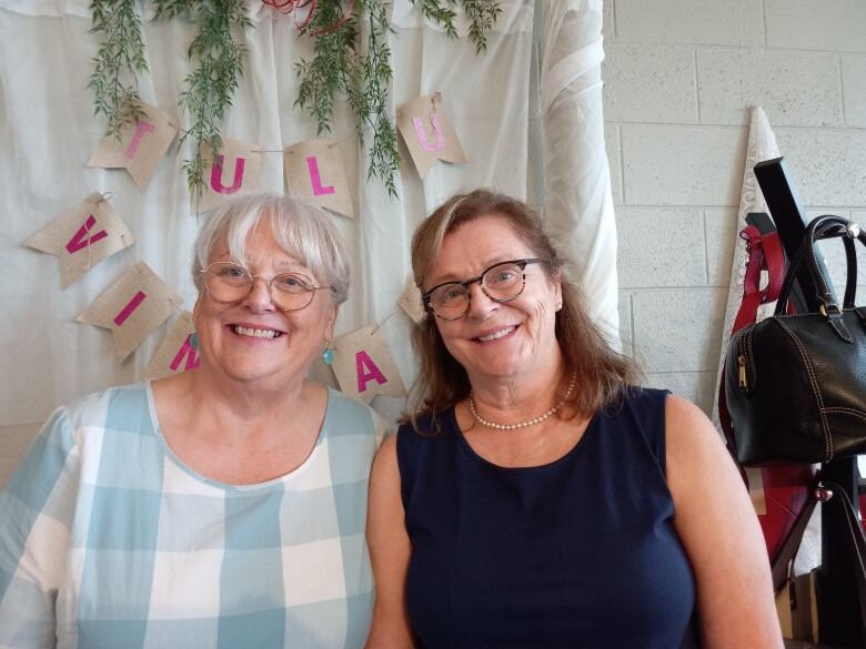 Two women standing together with sign TuLu Vintage behind them