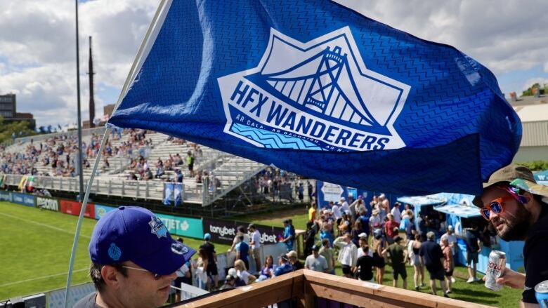 A blue and white flag waves in the air at a soccer game. It reads, 