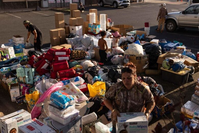 Volunteers carry and sort donated supplies in a parking lot.