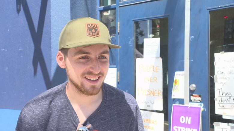 A man with a goatee and wearing a baseball hat smiles.