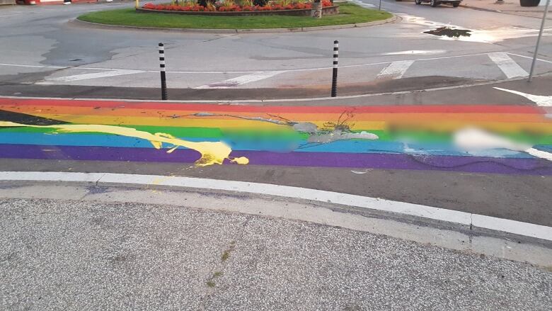 A rainbow crosswalk with obsenities blurred