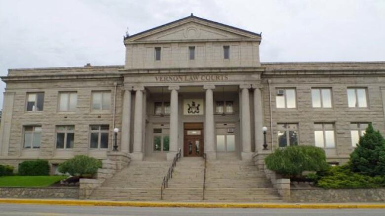 A rectangular, stone 2-story building with four pillars in the front with an inscription above the pillared entrance that reads, Vernon Law Courts below, which is the emblem of a crown.