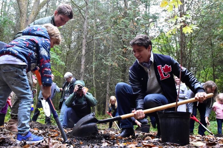 A family plants a tree in the woods.