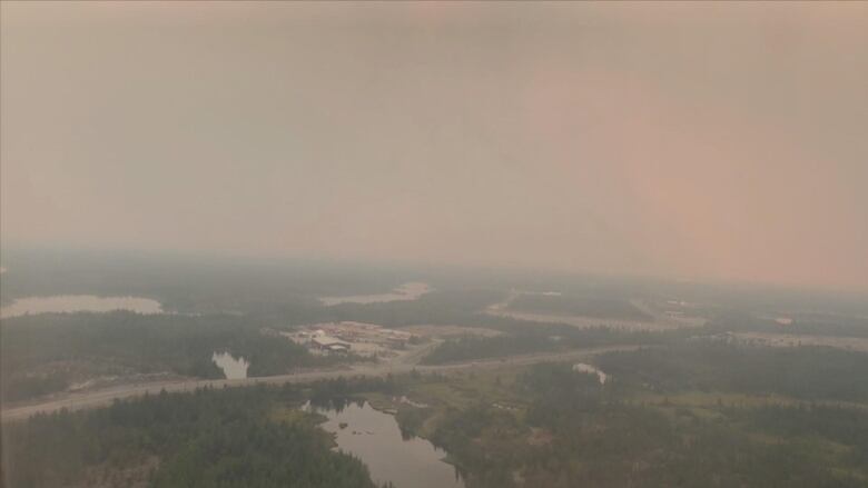 An aerial view of a rural town under a haze of smoke.