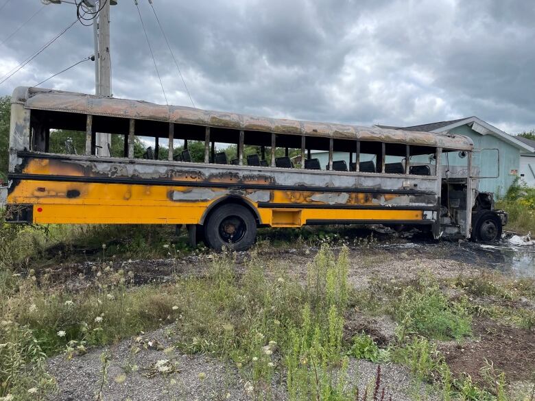 A burned bus sits in a field in Baddeck, N.S. 