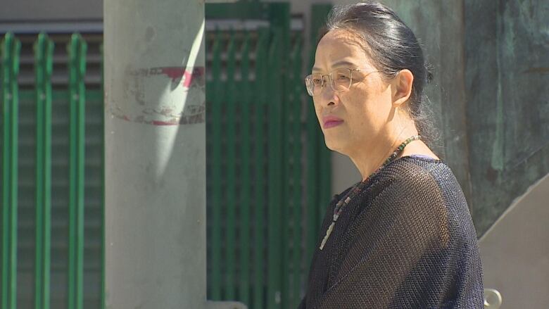 An East Asian woman wearing black is pictured in profile.