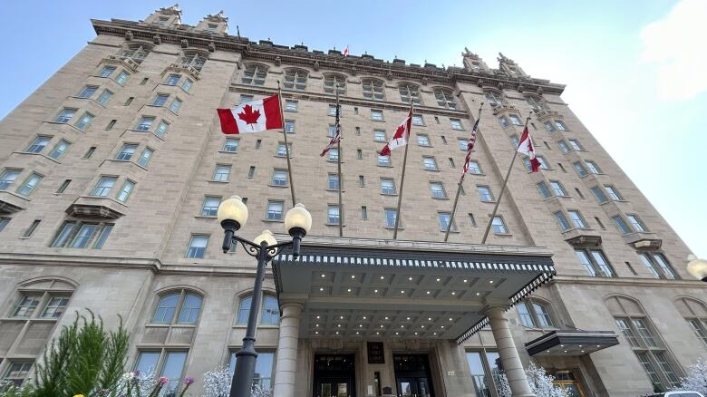 The exterior of a hotel is pictured. It has four Canadian flags raised at the front of it.