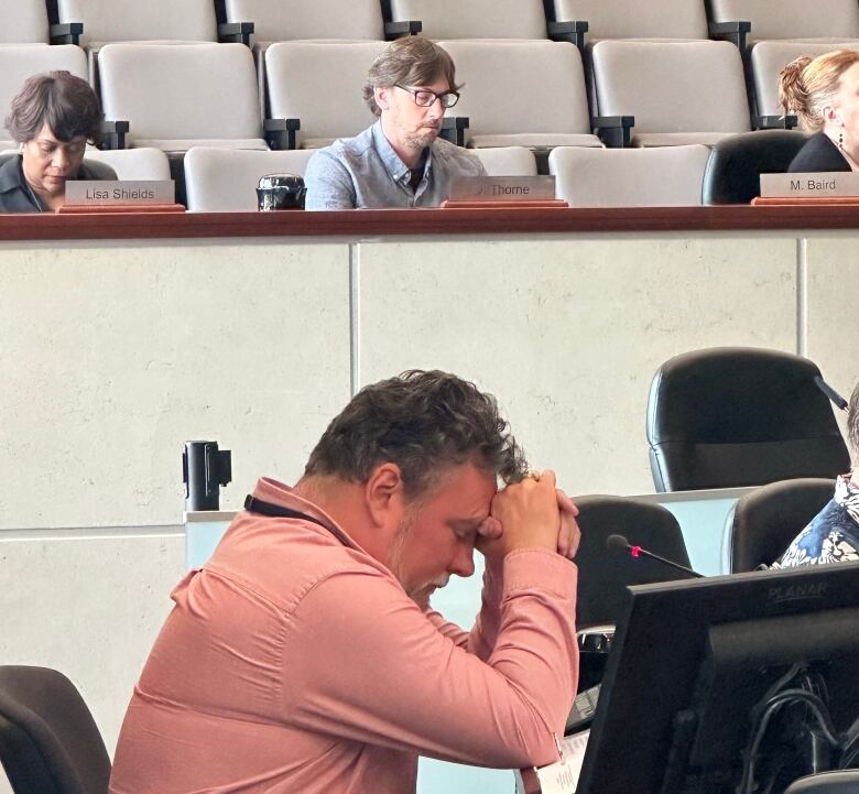 man sits at desk with hands clasped